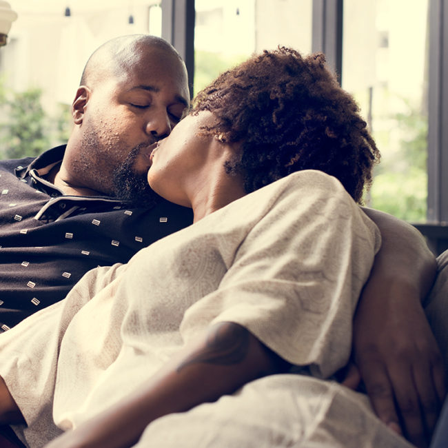 Black couple kissing on the couch