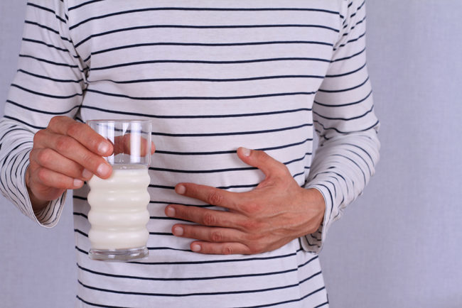 Man with stomach pain holding a glass of milk.