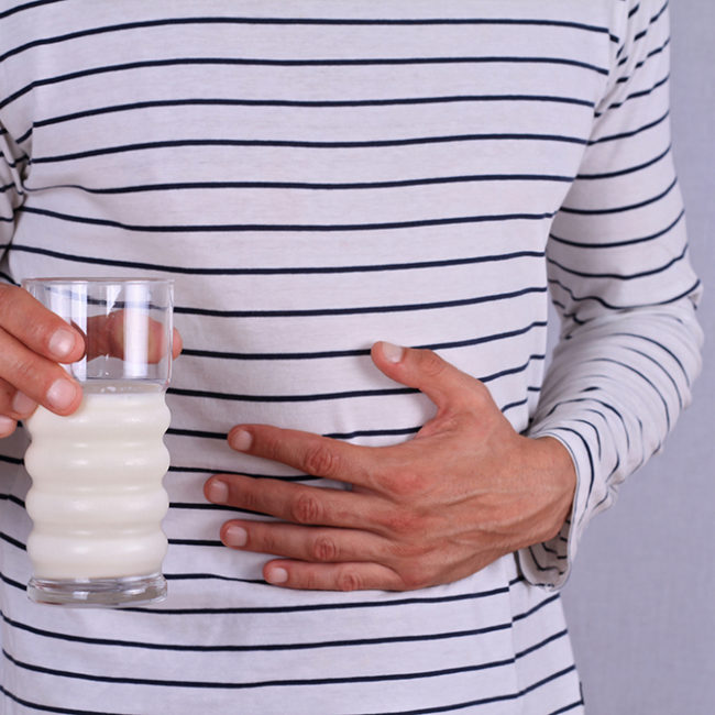 Man with stomach pain holding a glass of milk.