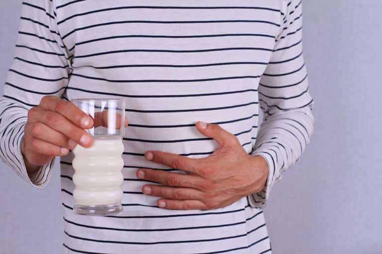 Man with stomach pain holding a glass of milk.