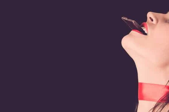 what-is-an-aphrodisiac Woman eating chocolate with her eyes closed